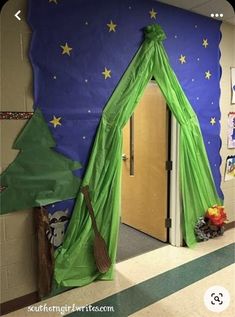 a room decorated for halloween with a green tent and broom on the floor, next to a door