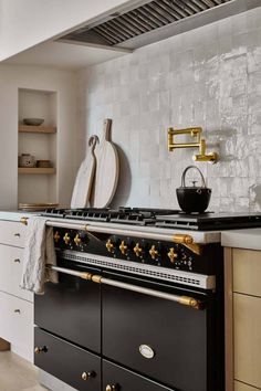 a stove top oven sitting inside of a kitchen next to white cupboards and drawers