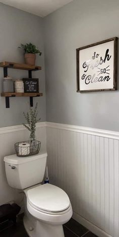 a white toilet sitting in a bathroom next to a wooden shelf filled with potted plants