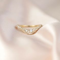 a close up view of a diamond ring on a white satin material with gold accents