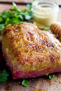 a piece of meat sitting on top of a wooden cutting board next to a jar of honey