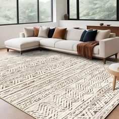 a living room with a large white couch and pillows on top of the area rug