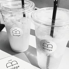 two plastic cups with straws are sitting on a table next to eachother