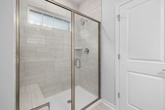 a walk in shower sitting inside of a bathroom next to a white door and window