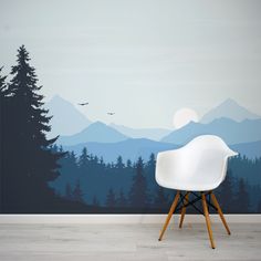 a white chair sitting in front of a wall with a forest mural on it's side