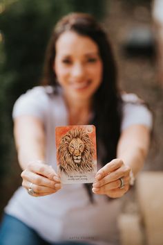 a woman holding up a card with a lion on it