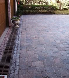 a fire hydrant sitting on the side of a brick road next to a garage