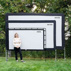 a woman standing in front of a large screen on top of a grass covered field