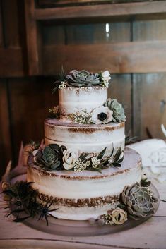 a three tiered cake with succulents and greenery