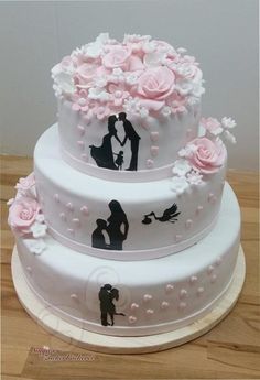 two tiered wedding cake decorated with pink flowers and silhouettes of people kissing each other