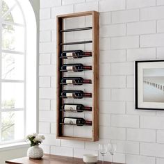 a wall mounted wine rack with several bottles on it next to a table in front of a window