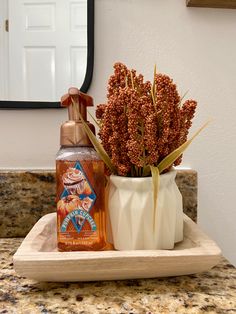 a bottle of hand sanitizer sitting next to a vase with flowers in it