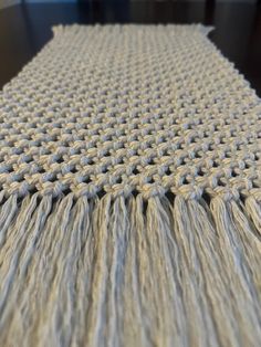 a close up view of a table cloth with fringes on it and a wooden table in the background