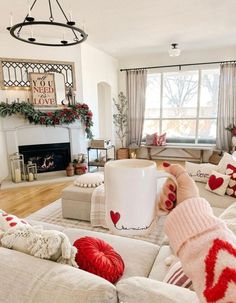 a living room filled with furniture and a fire place covered in christmas decorations on top of a hard wood floor