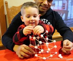 a man holding a small child in front of a table with an object on it