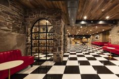 a large checkered floor with red couches and tables in the center, along with stone walls