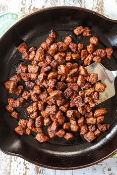 meat is being cooked in a skillet with a spoon