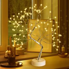 a lighted tree on a table next to a window