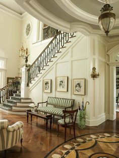 a living room filled with furniture next to a stair case on top of a hard wood floor