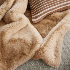 a brown and white blanket sitting on top of a couch