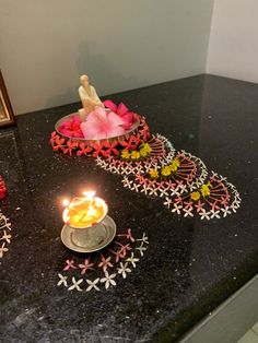 a lit candle sitting on top of a counter next to a bowl filled with flowers