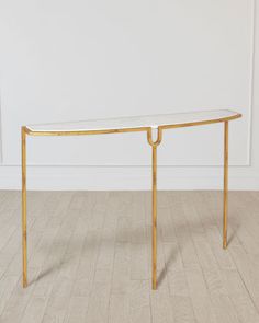 a gold and glass console table in an empty room with white walls, wood flooring and hardwood floors