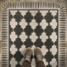 a person standing in front of a black and white tiled floor with brown shoes on it