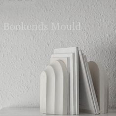 three books are stacked next to each other on a white shelf with the words bookends mould above them