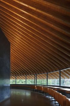 an empty room with benches and tables in front of a large wooden ceiling that is made of wood planks