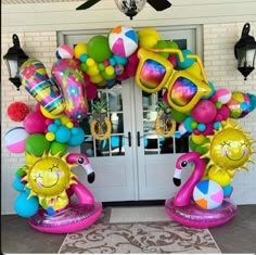 the entrance to a house decorated with balloons and sunflowers, beach balls, sunglasses and flip flops