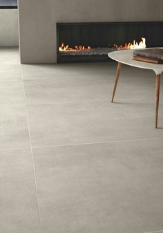 a living room with grey tile floors and a fireplace in the corner, next to a white coffee table