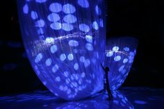 a person standing in front of a blue curtain with lights on it and an umbrella behind them