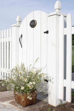 a white fence with a potted plant next to it