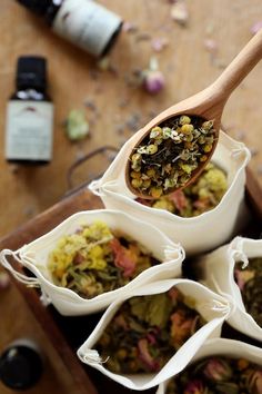 a wooden spoon filled with lots of different types of food in small white bags on top of a table