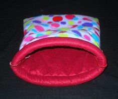 a colorful polka dot dog bed on a black background with red velvet pad and cover