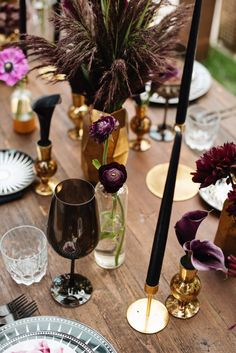 a wooden table topped with plates and vases filled with flowers