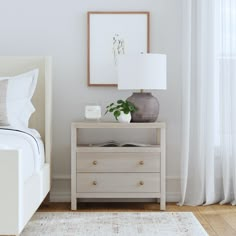 a bedroom with a bed, nightstand and pictures hanging on the wall next to it