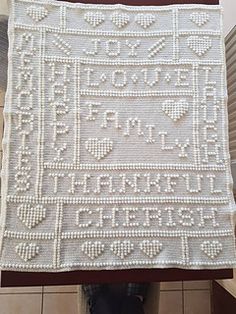 a white crocheted tablecloth on top of a wooden stand in front of a tiled wall