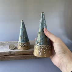 two small ceramic cones sitting on top of a wooden shelf