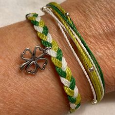 a close up of a person's arm wearing two bracelets with clover charms