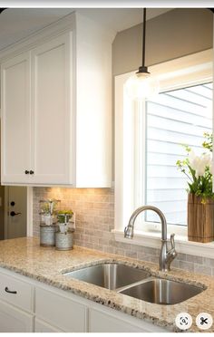 a kitchen with white cabinets and granite counter tops, along with a stainless steel sink