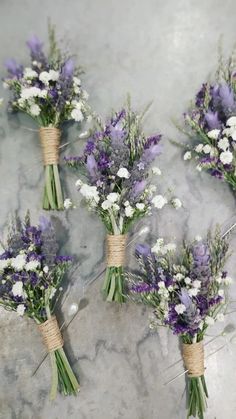 four bouquets of lavender and white flowers tied to twine on a marble surface