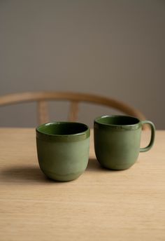 two green cups sitting on top of a wooden table