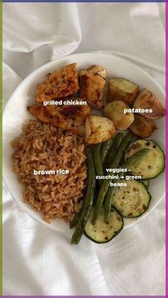 a white plate topped with rice and veggies next to fried chicken on top of brown rice