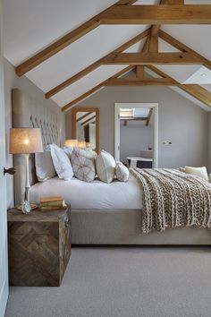 a large bed sitting under a wooden beam in a bedroom