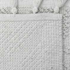 a white crocheted blanket with tassels on it