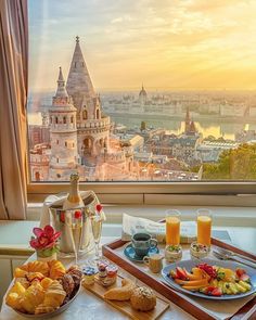 a table with food and drinks on it in front of a window overlooking the city