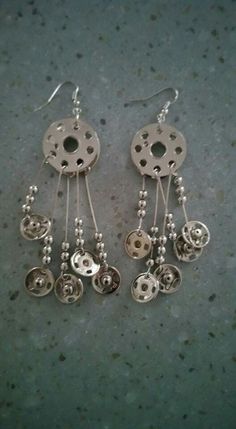 two pairs of silver earrings with beads hanging from it's sides on a gray surface