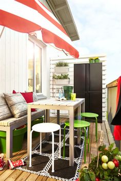 an outdoor patio with green and red chairs, tables and umbrellas on the deck