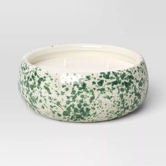 a white and green candle sitting inside of a bowl